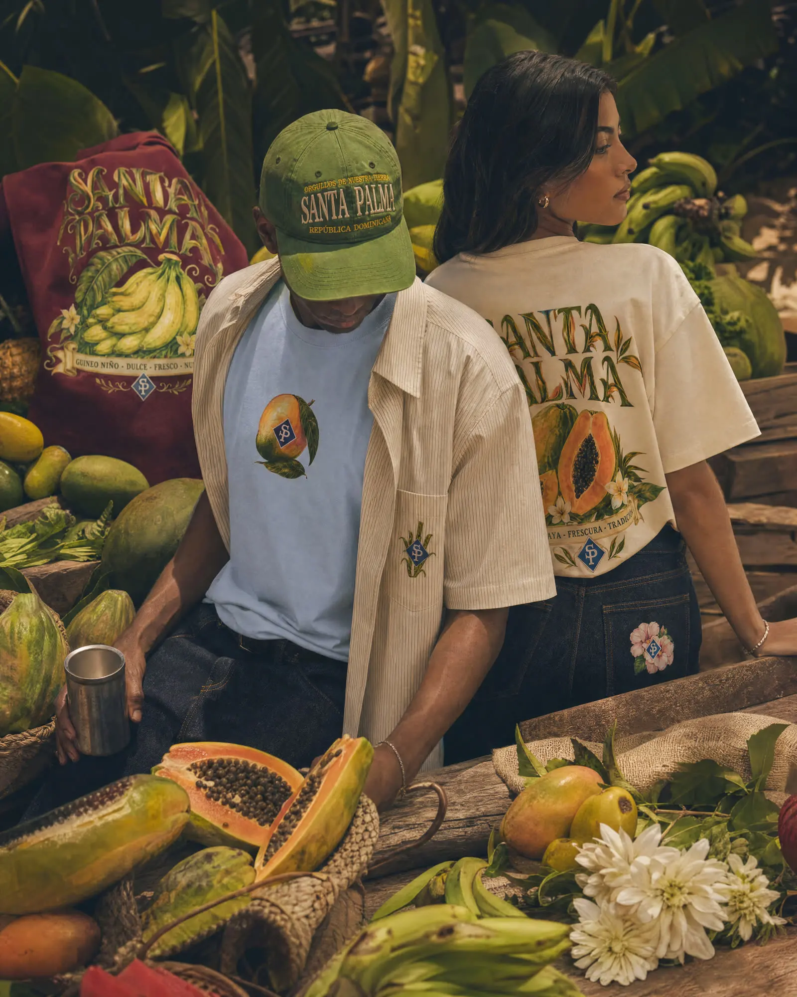 Dos figuras junto a una mesa cargada de fruta